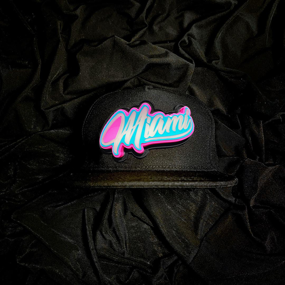 Black cap with a 3D Emblem 'Miami' in Pink that illuminate the logo on a black fabric background